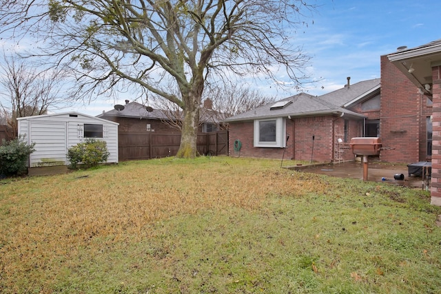 view of yard featuring fence, a storage unit, and an outdoor structure