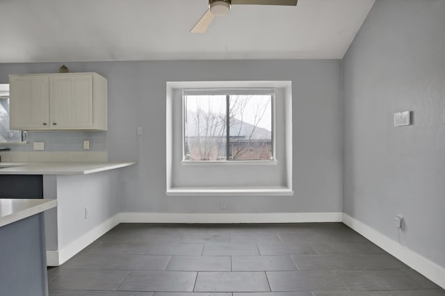 unfurnished dining area with a ceiling fan and baseboards