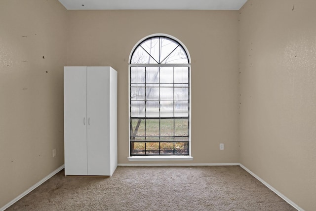 carpeted empty room featuring baseboards