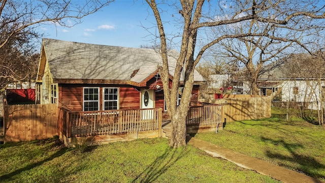 view of front of home featuring a front lawn, roof with shingles, and fence