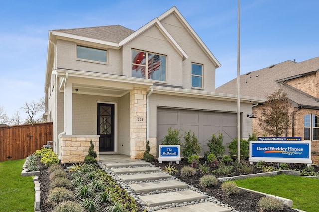 view of front of home featuring brick siding, roof with shingles, fence, a garage, and stone siding