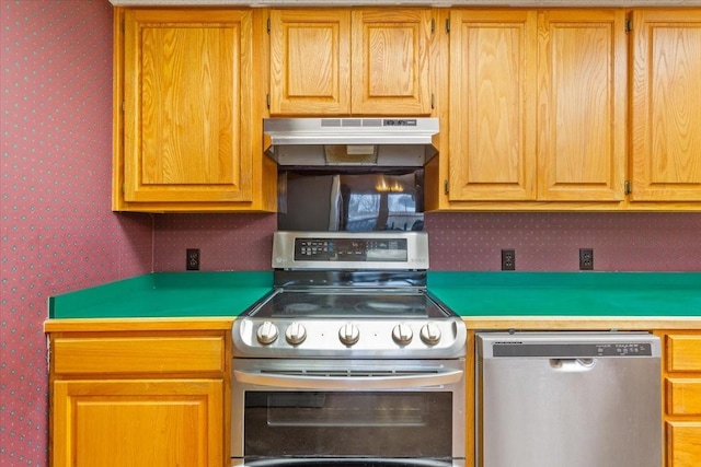 kitchen with under cabinet range hood, appliances with stainless steel finishes, light countertops, and wallpapered walls