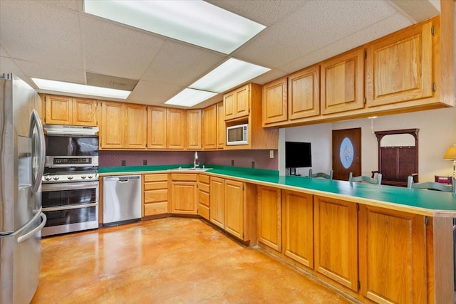 kitchen featuring under cabinet range hood, stainless steel appliances, a peninsula, concrete floors, and light countertops