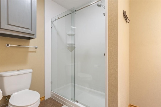 bathroom featuring a stall shower and toilet