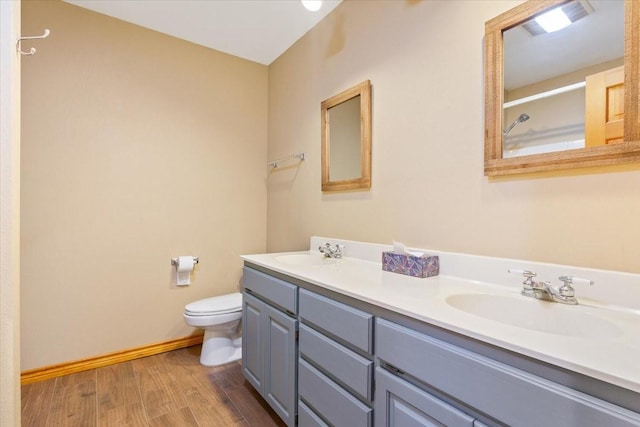 full bathroom with double vanity, toilet, a sink, and wood finished floors