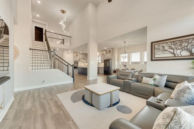 hall featuring french doors, light wood-style floors, baseboards, and a towering ceiling