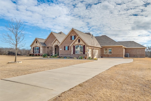 view of front of home with a front lawn, brick siding, driveway, and an attached garage