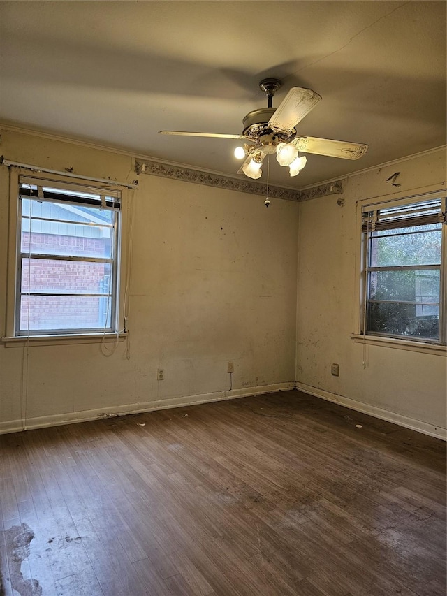 spare room with dark wood-type flooring, a wealth of natural light, and a ceiling fan