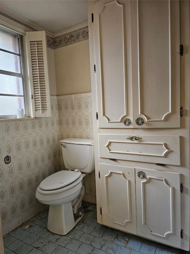 bathroom featuring a wainscoted wall, toilet, and wallpapered walls