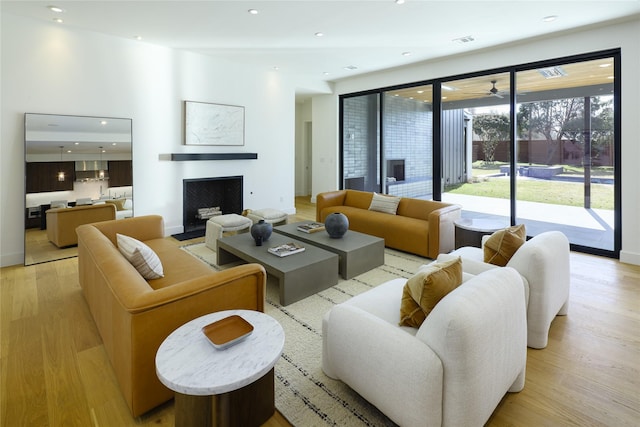 living room featuring light wood-type flooring, a fireplace, visible vents, and recessed lighting