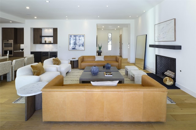 living room featuring light wood-type flooring, a fireplace, baseboards, and recessed lighting