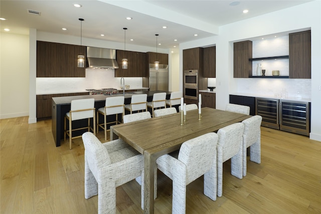 dining space featuring beverage cooler, light wood-type flooring, baseboards, and recessed lighting