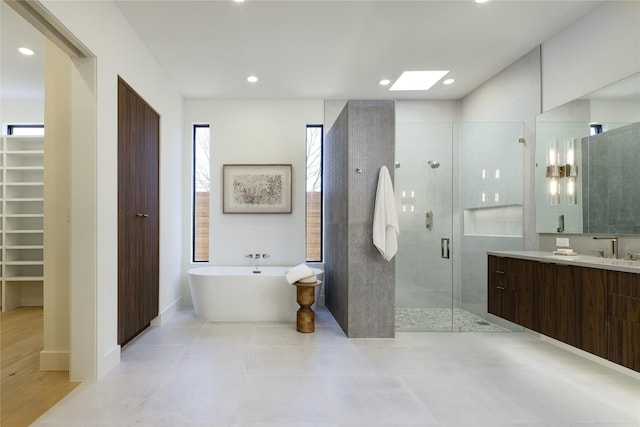 full bath featuring recessed lighting, vanity, a freestanding bath, a spacious closet, and a stall shower