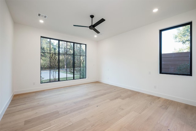 empty room with a healthy amount of sunlight, light wood-type flooring, visible vents, and recessed lighting