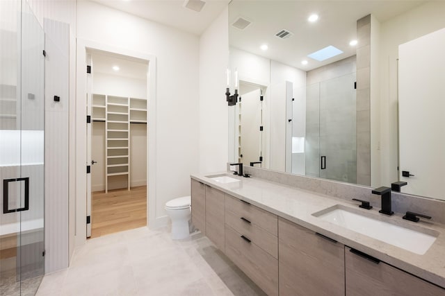 bathroom featuring a stall shower, visible vents, a sink, and a spacious closet