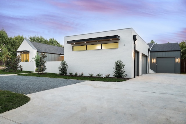 view of front of house featuring driveway, brick siding, board and batten siding, and an attached garage