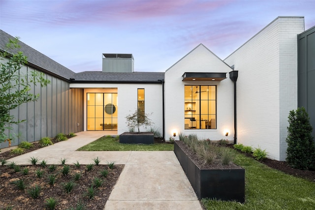 back of house at dusk with a patio and brick siding