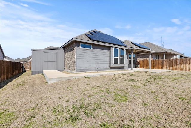 rear view of property with an outbuilding, a storage shed, roof mounted solar panels, a patio area, and a fenced backyard