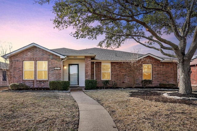 single story home with roof with shingles, a front yard, and brick siding