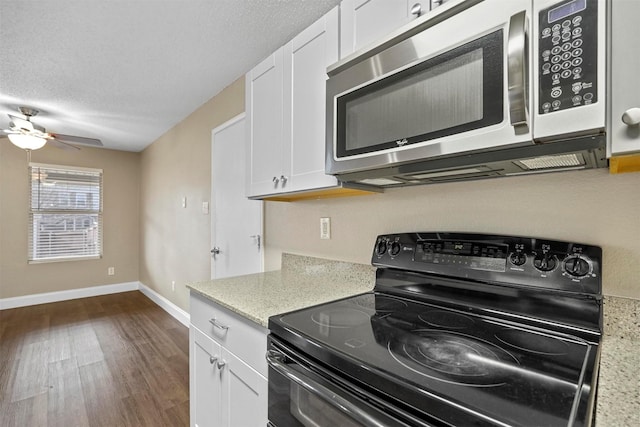 kitchen featuring stainless steel microwave, dark wood-type flooring, a textured ceiling, black electric range, and white cabinetry