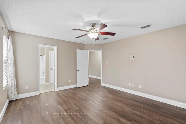 unfurnished bedroom with dark wood-style floors, visible vents, a textured ceiling, and baseboards