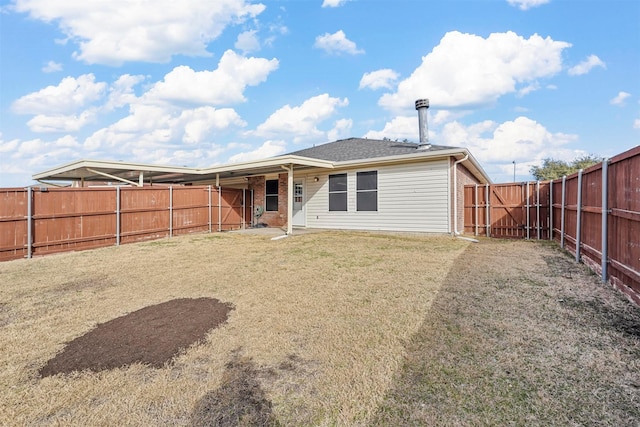 rear view of property featuring a yard, brick siding, and a fenced backyard