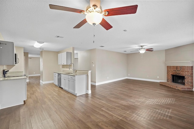 kitchen featuring stainless steel appliances, a sink, visible vents, open floor plan, and light countertops