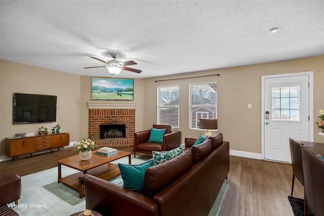 living area with light wood-type flooring, a fireplace, plenty of natural light, and a textured ceiling