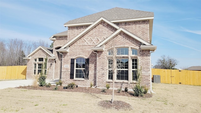 french country style house featuring a gate, fence, central AC, and brick siding