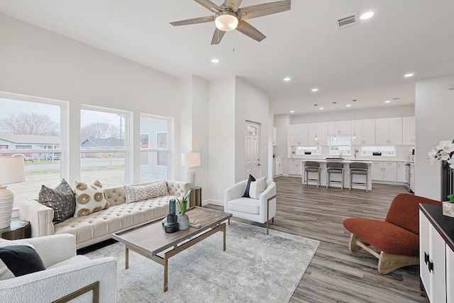 living room featuring light wood-style floors, baseboards, visible vents, and recessed lighting