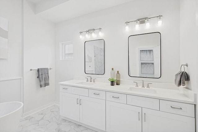 full bathroom featuring marble finish floor, a sink, baseboards, and double vanity