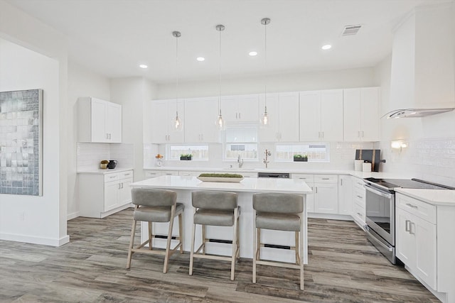 kitchen featuring decorative light fixtures, light countertops, white cabinetry, and electric range