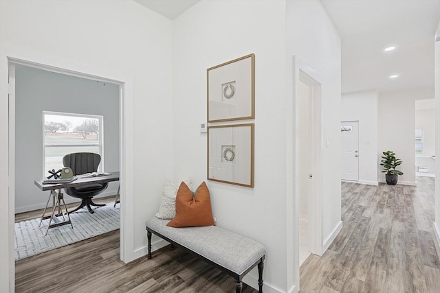 hallway featuring baseboards, wood finished floors, and recessed lighting