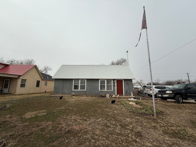 view of front of home with metal roof, a front lawn, and stucco siding