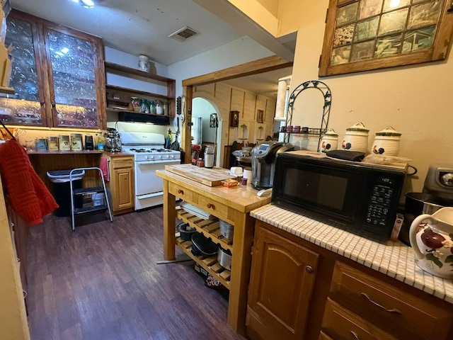 kitchen with dark wood-style floors, gas range gas stove, visible vents, light countertops, and black microwave