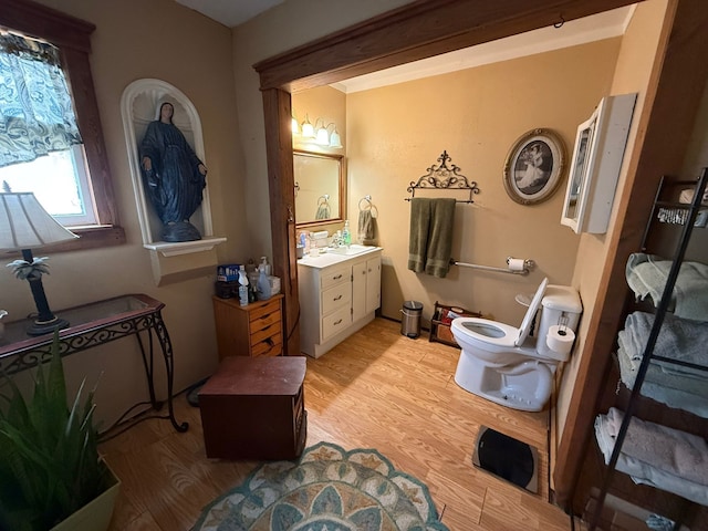 bathroom with toilet, wood finished floors, vanity, and crown molding