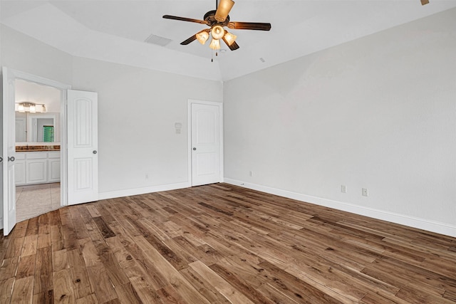 unfurnished bedroom with ensuite bathroom, wood finished floors, a ceiling fan, visible vents, and baseboards