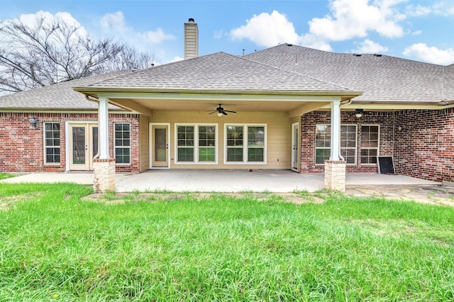 back of property with a patio, brick siding, a shingled roof, a ceiling fan, and a chimney