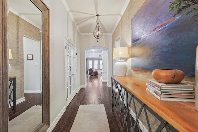 hall with ornamental molding, arched walkways, dark wood-style flooring, and baseboards