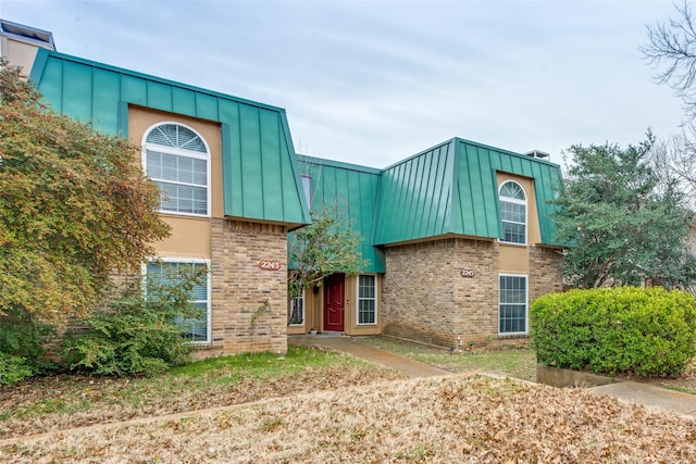 view of front of house featuring a standing seam roof, brick siding, and metal roof