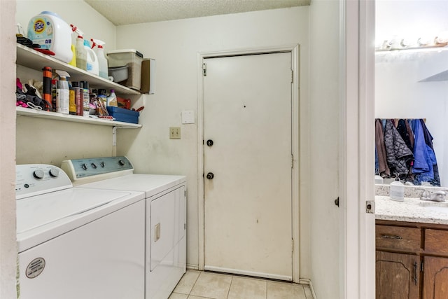 washroom with laundry area, light tile patterned floors, a textured ceiling, separate washer and dryer, and a sink