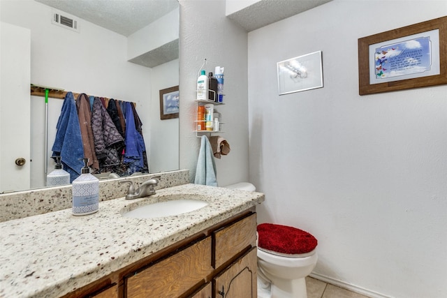 half bath featuring tile patterned flooring, visible vents, vanity, and toilet