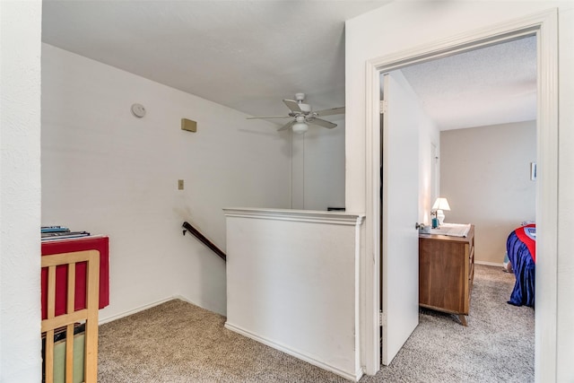 hallway featuring baseboards, light colored carpet, and an upstairs landing