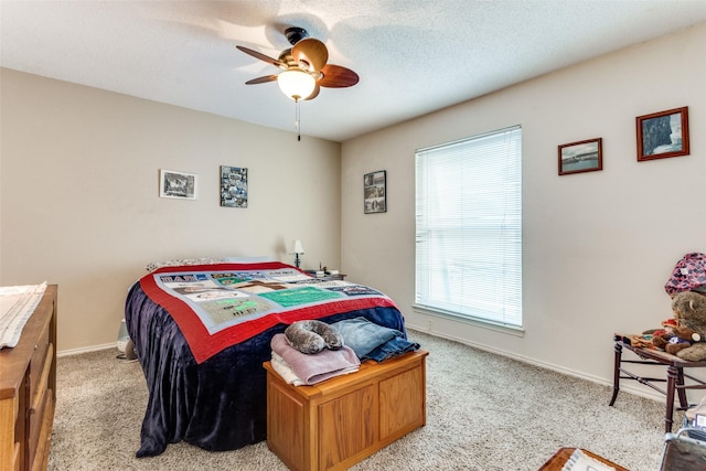 bedroom featuring light carpet, ceiling fan, a textured ceiling, and baseboards