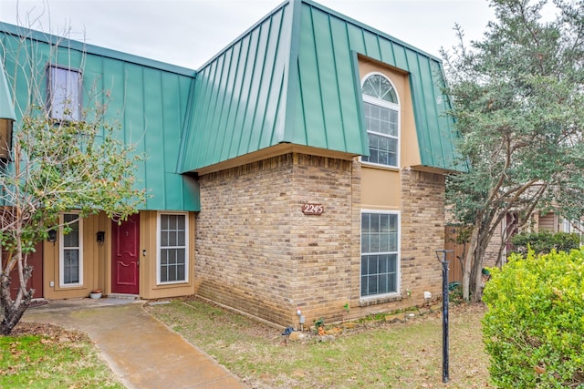 view of front of home featuring a standing seam roof, metal roof, and brick siding