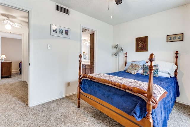 carpeted bedroom with a textured ceiling, baseboards, visible vents, and ensuite bathroom