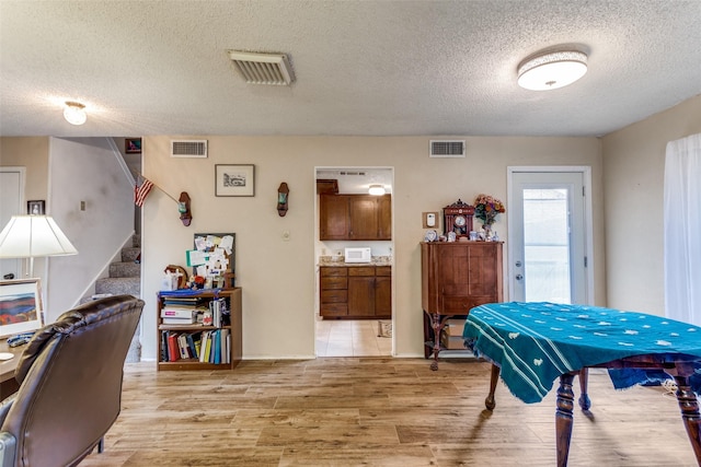 dining room with stairway, visible vents, and light wood-style floors