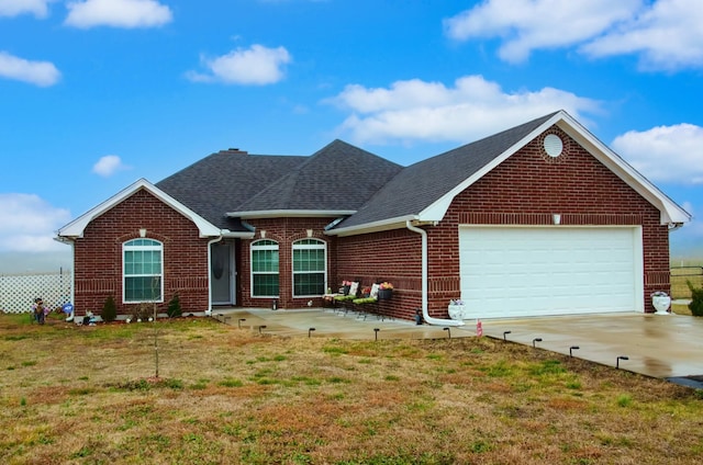 ranch-style home featuring a garage, a shingled roof, concrete driveway, a front lawn, and brick siding