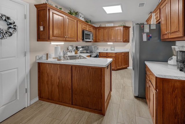 kitchen featuring visible vents, light countertops, appliances with stainless steel finishes, a sink, and a peninsula