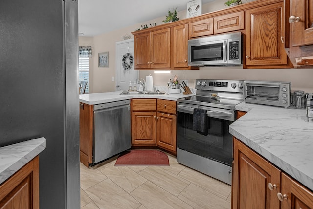 kitchen with a toaster, appliances with stainless steel finishes, light countertops, and a sink